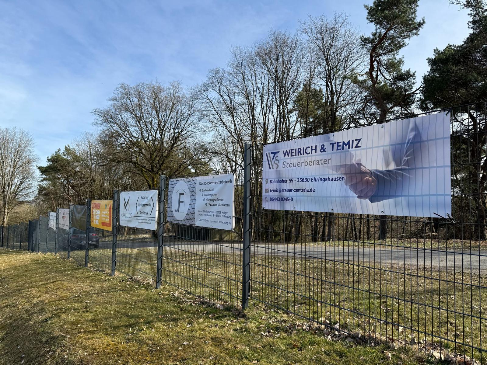 Großformatige Werbebanner an einem Zaun im Außenbereich