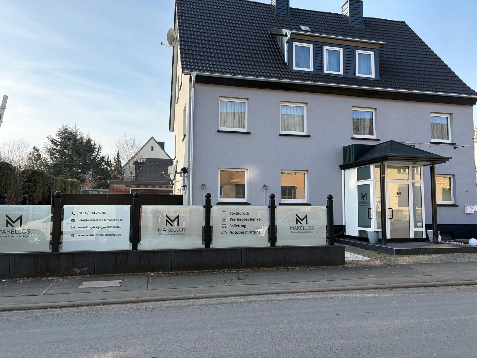 Außenansicht eines Unternehmens mit beschrifteten Glasfeldern und Eingang